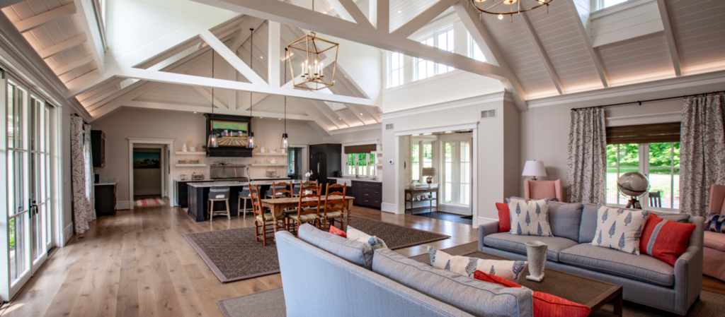living room with tan colored wood floor sitting beneath timber beams in ceiling with furniture sitting throughout the space