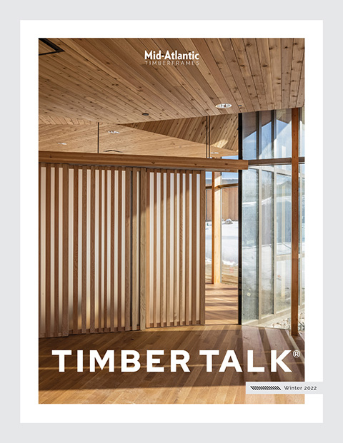 Cover of Timber Talk magazine showing a modern interior with wooden floors, ceiling, and slatted wall panels, large glass windows, and natural sunlight streaming in. Text reads Mid-Atlantic Timberframes and Winter 2022.